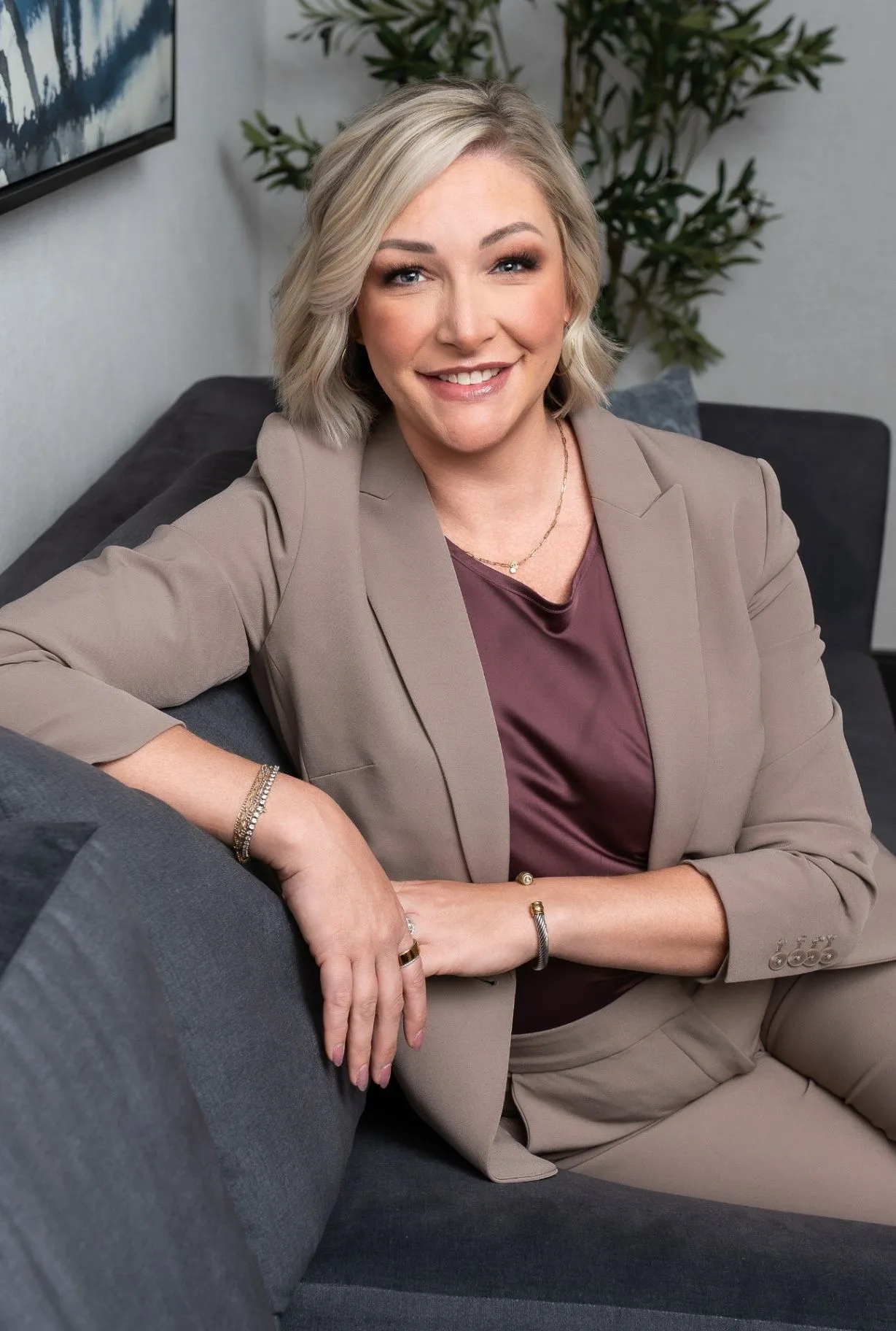 April Stewart seated indoors in a relaxed portrait, smiling toward the camera