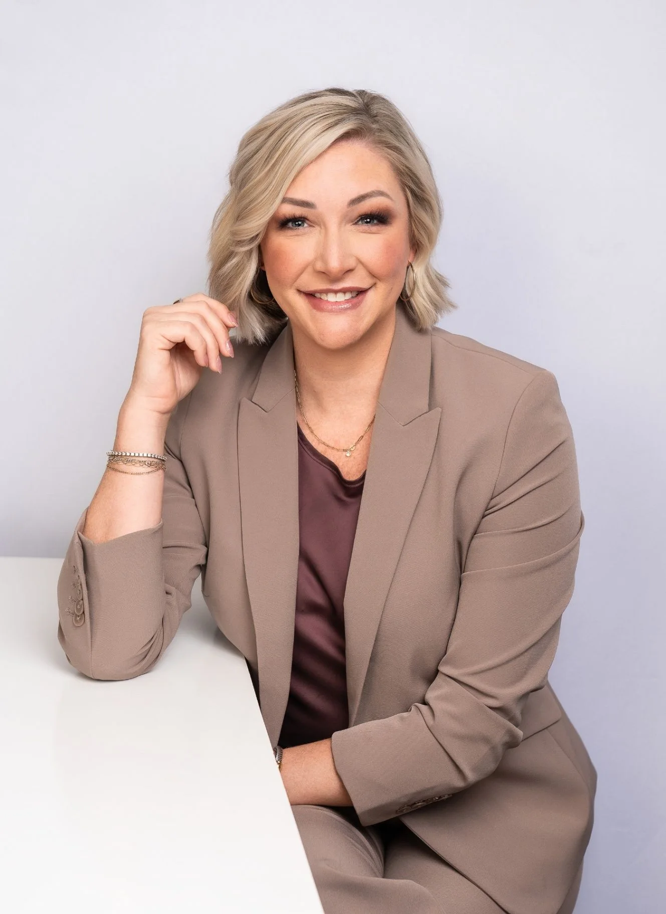 April Stewart smiling in a warm portrait at a desk, wearing a neutral blazer